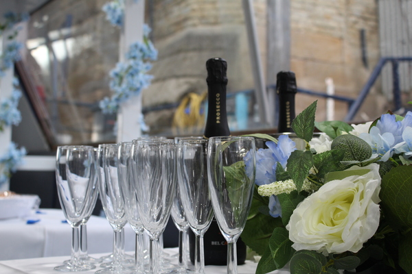 Champagne bottle and glasses set among white and blue flowers