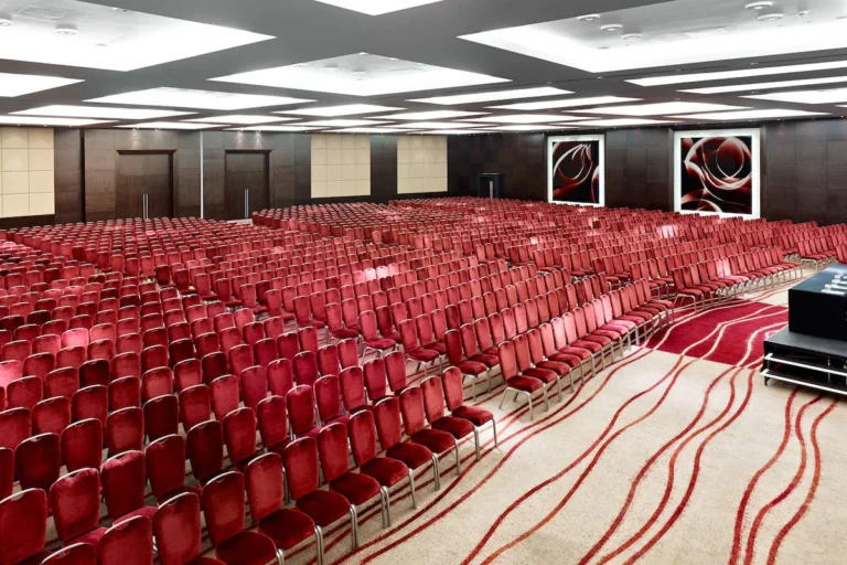 Ballroom set theatre-style with rows of red seats facing a stage