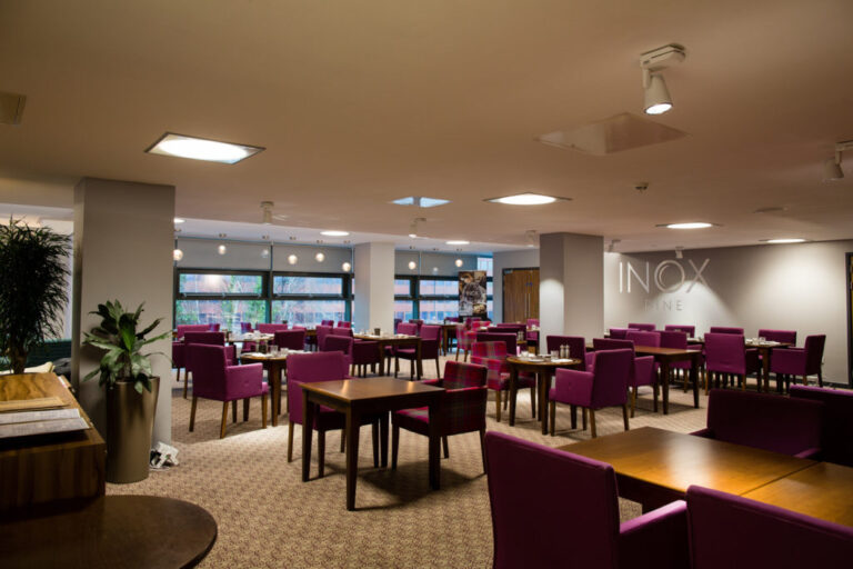 INOX breakout area with dining tables and purple upholstered chairs