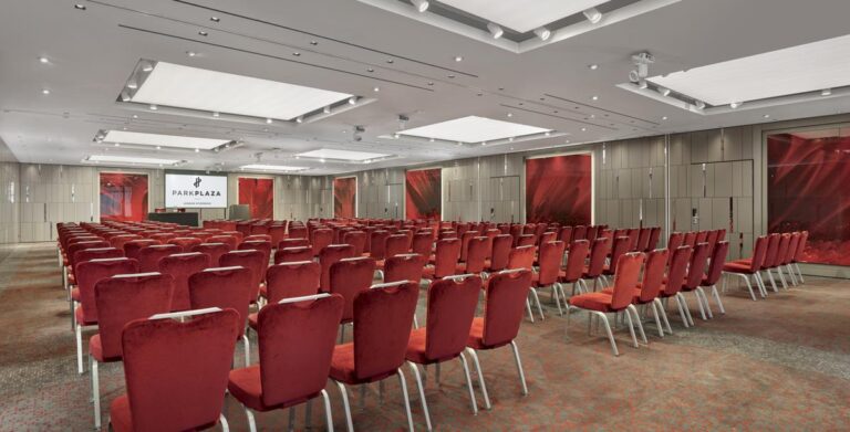 Theatre-style conference room with rows of red velvet chairs facing a Park Plaza screen.
