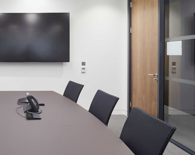 Small meeting room with a wall screen, round table and three chairs