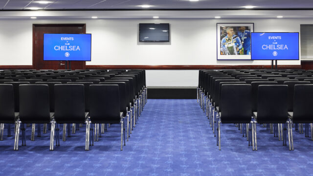 Theatre-style conference room with rows of chairs facing presentation screens