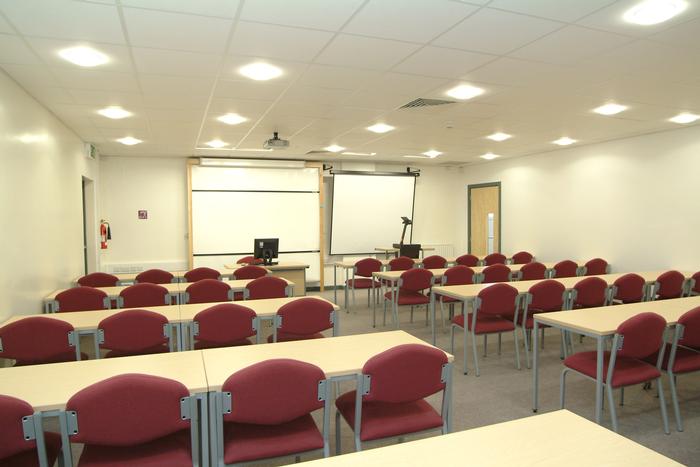 Conference room set classroom-style with red chairs and twin screens