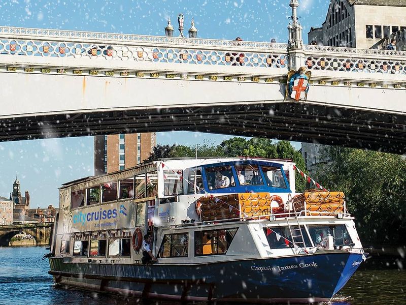 Sightseeing boat cruising past a stone bridge on a sunny day