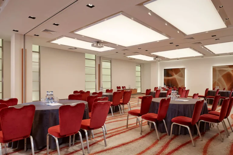 Double Edward Rooms set cabaret-style with round tables, red velvet chairs and abstract art panels.