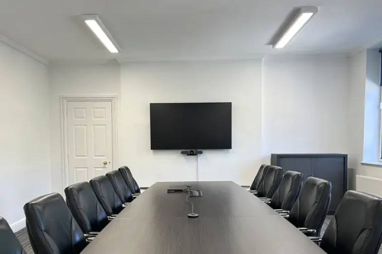 Executive Boardroom with a dark table, black chairs and a wall screen