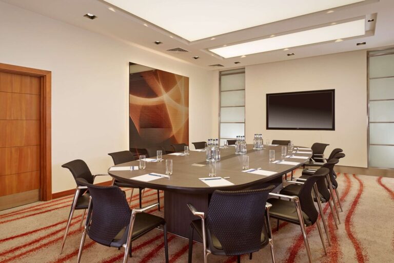 Boardroom with an oval table, black leather chairs and a wall screen