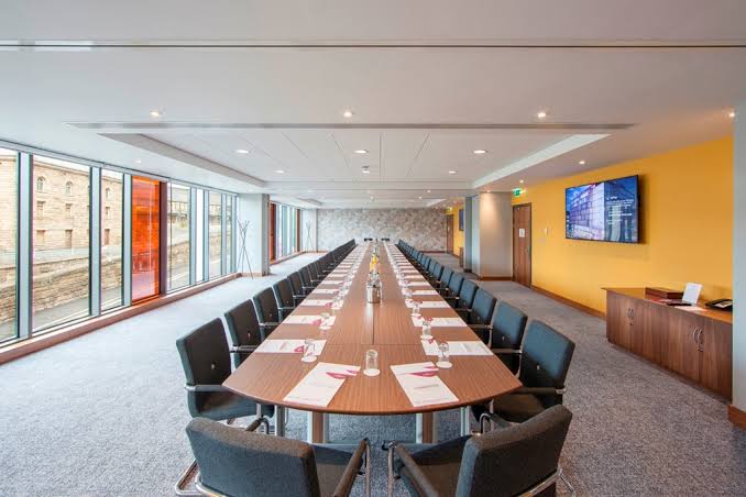 Locomotion Suite with a long boardroom table and orange feature wall
