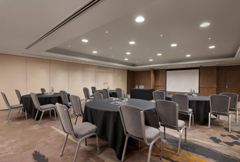 Gunnel Suite set cabaret-style with round tables and a projector screen