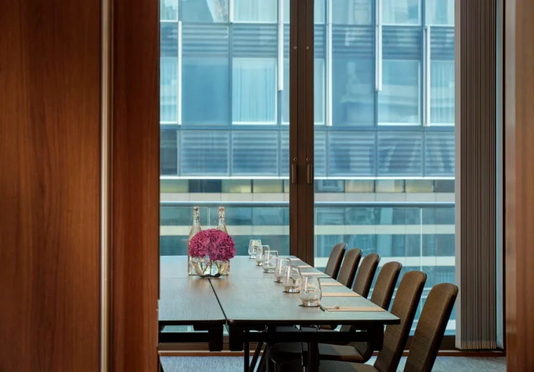 Lambeth meeting room with a glass table, pink flowers and floor-to-ceiling windows.