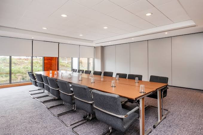 Locomotion Suite boardroom table with grey chairs and a garden view