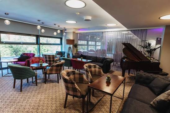 Lounge with tartan armchairs, sofas and a grand piano