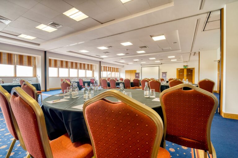 Lynx Conference Centre set boardroom-style with orange chairs and a screen