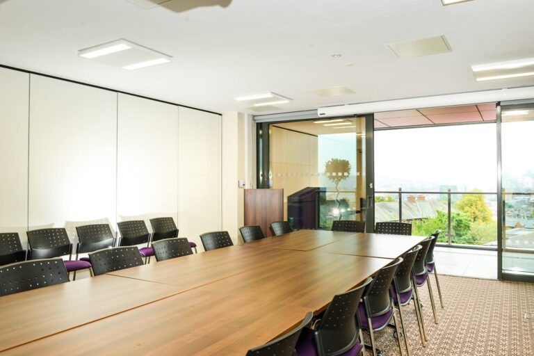 Meeting room with a long table, patterned chairs and a city view