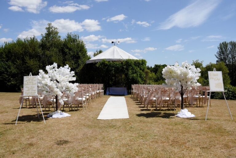 Outdoor wedding ceremony setup with a gazebo, white aisle and blossom trees