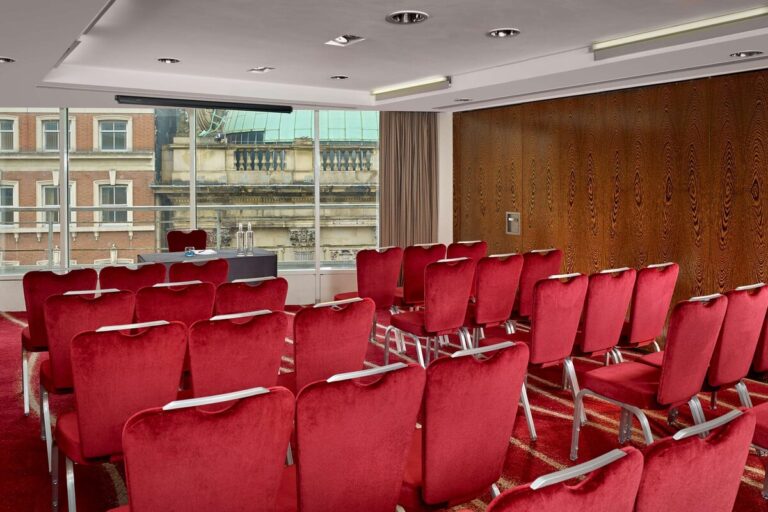 Theatre-style seating facing a lectern table, with a wood-panelled wall and city view.