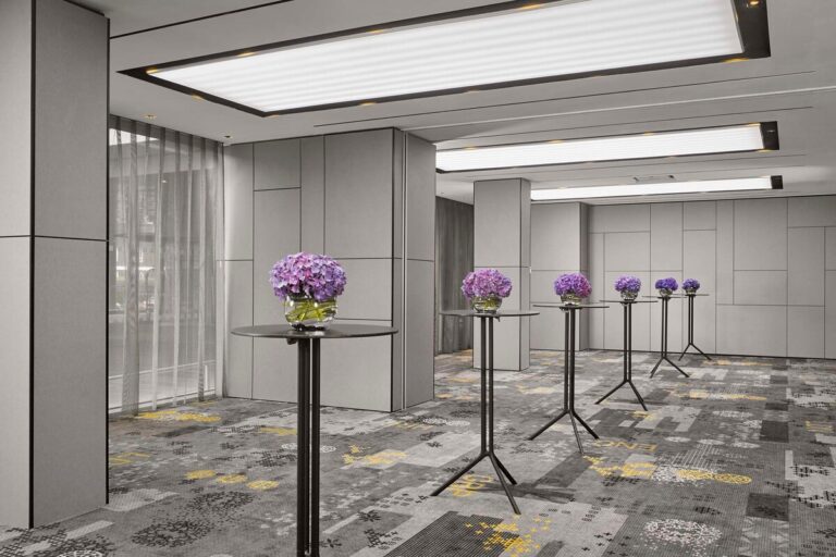Reception area with high cocktail tables, purple hydrangea arrangements and patterned carpet.