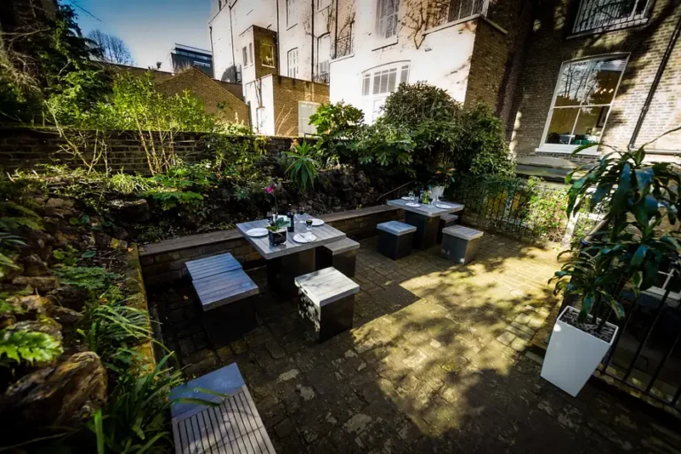 Private garden courtyard with plants, small tables and terraced houses