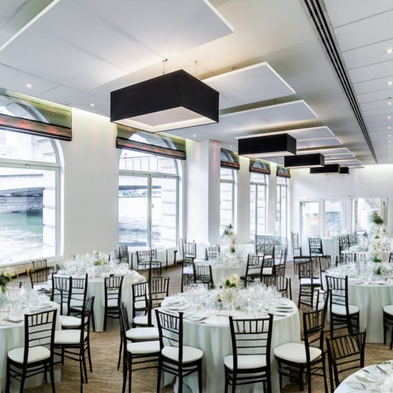 River Room with long dining tables set beneath black pendant lights