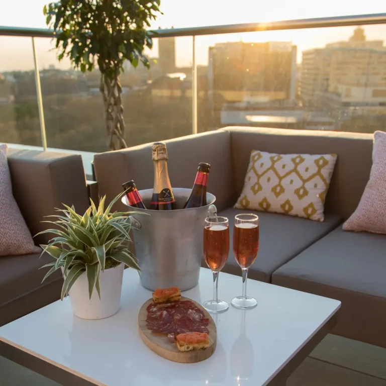 Rooftop terrace lounge with a champagne bucket, charcuterie board and sunset skyline view.