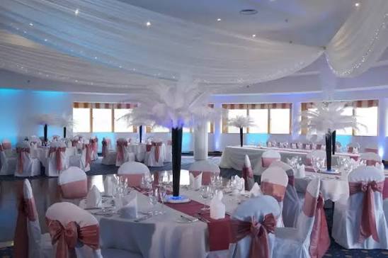 Roundall room set for a wedding with feather centrepieces and pink chair covers