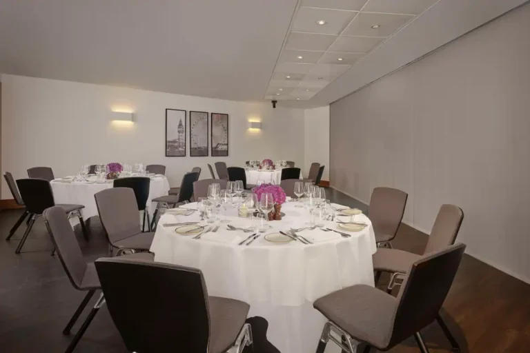 Terrace Suite set for private dining with round tables, pink flowers and framed prints.