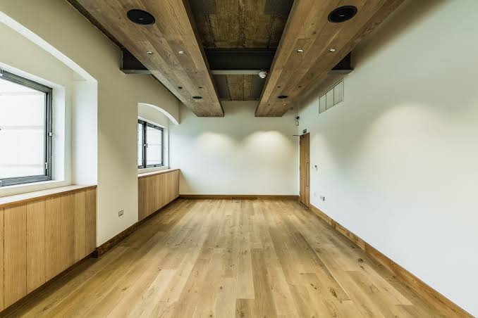 Empty Thames Room with wooden flooring, exposed beams and tall windows