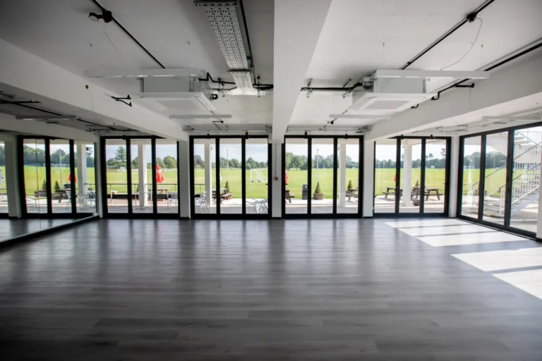 The Studio with a wood floor and glass folding doors overlooking a sports field