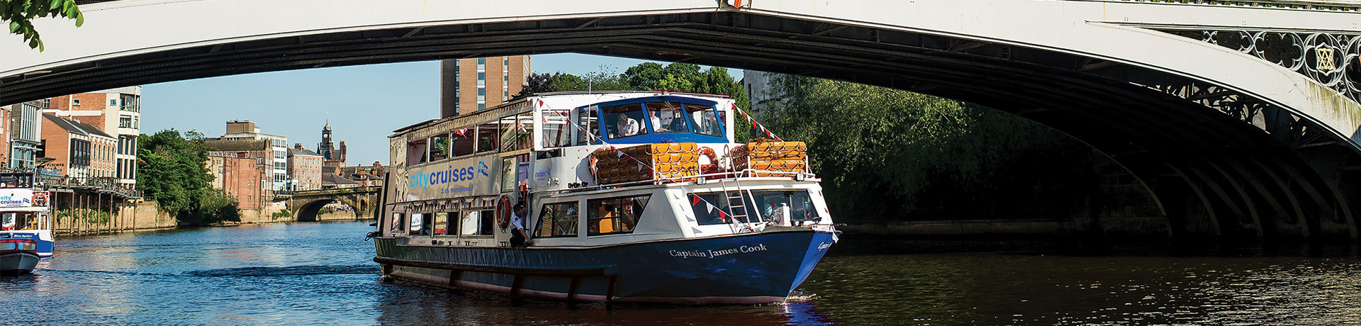 Captain James Cook boat passing beneath an ornate bridge on the river