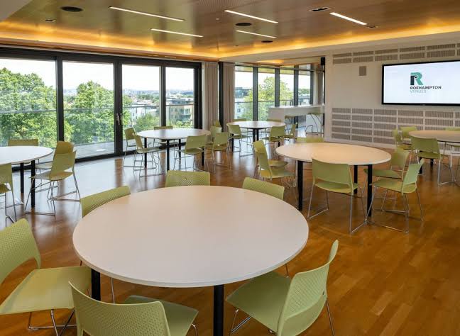 Lime Tree Suite with round white tables, green chairs and floor-to-ceiling windows.