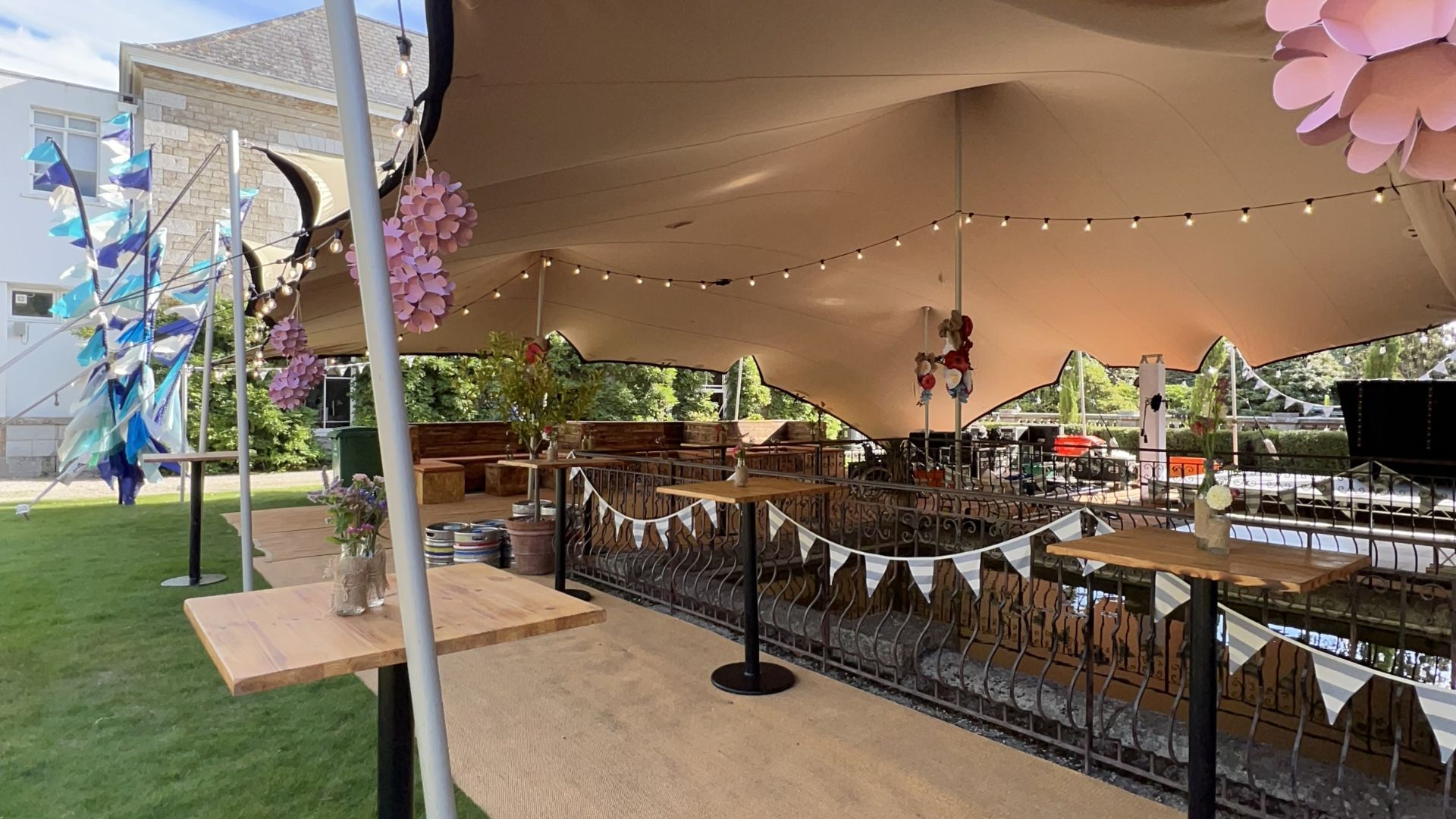 Stretch tent with festoon lighting and bunting set up beside a canal