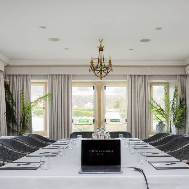 Boardroom at Lords of the Manor with a long table, chandelier and garden views