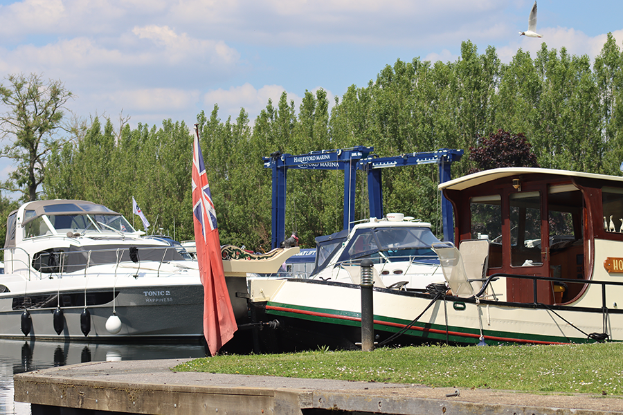 Boats moored at Harleyford Marina with a red ensign flag and boat hoist crane.