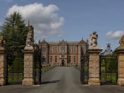 Grand entrance gates and driveway leading to the hall's stone facade