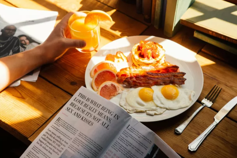 Full English breakfast plate with eggs, bacon and pancakes beside an open magazine