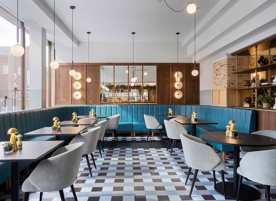 Restaurant seating with teal booths, round tables and pendant lighting