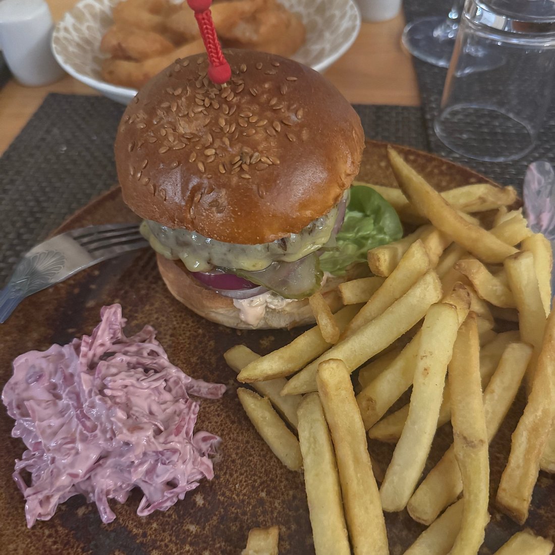 Burger and chips served with coleslaw on a rustic plate