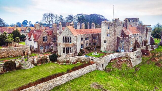 Aerial view of Lympne Castle's stone buildings and battlements surrounded by green lawns