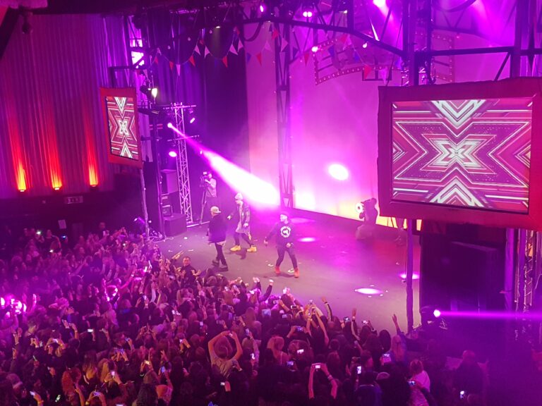 Main auditorium stage lit purple with a large crowd and video screen